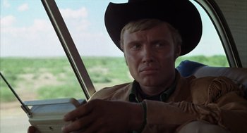 Movie still from “Midnight Cowboy” (1969), directed by John Schlesinger – A man wearing a cowboy hat sitting in a car; Close Up shot, Over the shoulder angle