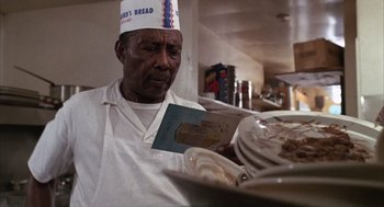 Movie still from “Midnight Cowboy” (1969), directed by John Schlesinger – An old man wearing a white hat is holding a plate of food; Close Up shot, Low angle