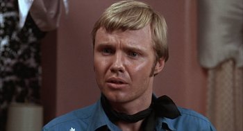 Movie still from “Midnight Cowboy” (1969), directed by John Schlesinger – A person wearing a blue shirt and a black neck tie; Close Up shot, Over the shoulder angle