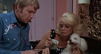 Movie still from “Midnight Cowboy” (1969), directed by John Schlesinger – A man and a woman holding a phone and a dog; Medium shot, Over the shoulder angle