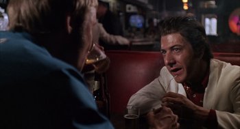 Movie still from “Midnight Cowboy” (1969), directed by John Schlesinger – Two men are sitting at a table with drinks in front of them; Close Up shot, Over the shoulder angle