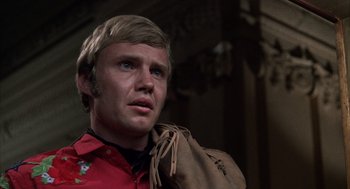 Movie still from “Midnight Cowboy” (1969), directed by John Schlesinger – A man with a bag in his hand and wearing a red shirt; Close Up shot, Low angle