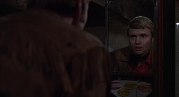Movie still from “Midnight Cowboy” (1969), directed by John Schlesinger – A man looking in the mirror in front of a mirror; Close Up shot, Over the shoulder angle
