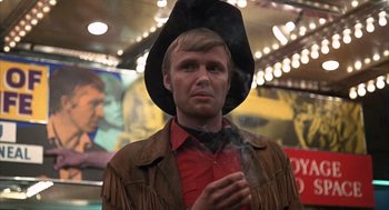 Movie still from “Midnight Cowboy” (1969), directed by John Schlesinger – A man wearing a cowboy hat and holding a cigarette in his hand; Close Up shot, Low angle