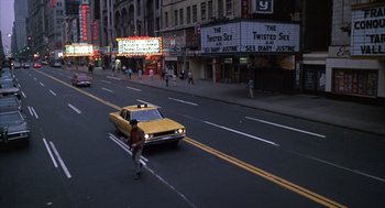 Movie still from “Midnight Cowboy” (1969), directed by John Schlesinger – A man is crossing the street in front of a yellow taxi cab; Extreme Wide shot, High angle