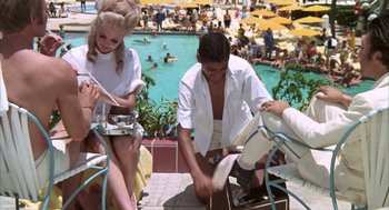 Movie still from “Midnight Cowboy” (1969), directed by John Schlesinger – A group of people sitting around a swimming pool; Medium shot, High angle