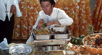 Movie still from “Midnight Cowboy” (1969), directed by John Schlesinger – A man sitting at a table with a tray of food; Medium shot, High angle