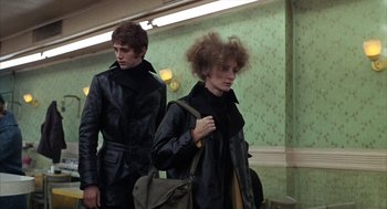 Movie still from “Midnight Cowboy” (1969), directed by John Schlesinger – A man and a woman are walking down a hallway; Medium shot, Low angle