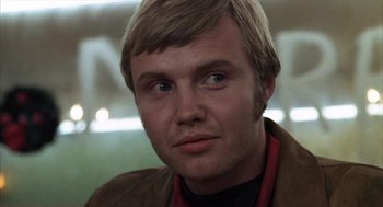 Movie still from “Midnight Cowboy” (1969), directed by John Schlesinger – A person wearing a brown jacket; Close Up shot, Low angle