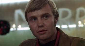 Movie still from “Midnight Cowboy” (1969), directed by John Schlesinger – A person wearing a brown jacket; Close Up shot, Low angle