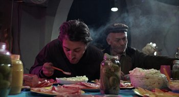 Movie still from “Midnight Cowboy” (1969), directed by John Schlesinger – Two men sitting at a dinner table eating food; Medium shot, Low angle