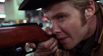 Movie still from “Midnight Cowboy” (1969), directed by John Schlesinger – A man holding a gun up to his face; Close Up shot, Over the shoulder angle