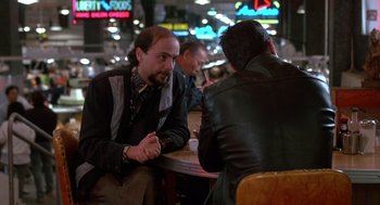 Movie still from “Midnight Run” (1988), directed by Martin Brest – Two men sitting at a table talking to each other; Medium shot, Over the shoulder angle