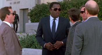 Movie still from “Midnight Run” (1988), directed by Martin Brest – A man in a suit talks to a man in a suit; Medium shot, Low angle