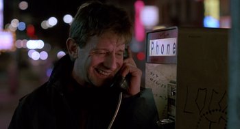 Movie still from “Midnight Run” (1988), directed by Martin Brest – A man talking on a phone at a phone booth at night; Close Up shot, Low angle