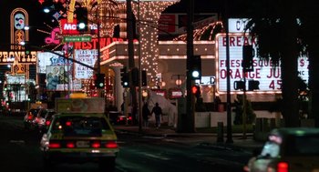 Movie still from “Midnight Run” (1988), directed by Martin Brest – A busy city street at night lit up with lights; Extreme Wide shot, Low angle