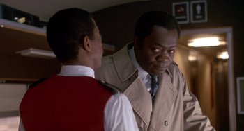 Movie still from “Midnight Run” (1988), directed by Martin Brest – Two men standing next to each other in front of a wall; Medium shot, Low angle