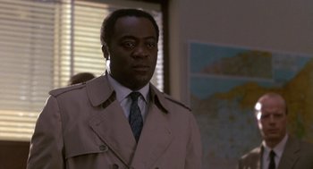 Movie still from “Midnight Run” (1988), directed by Martin Brest – A man wearing a trench coat and tie; Close Up shot, Low angle