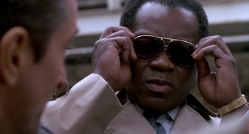 Movie still from “Midnight Run” (1988), directed by Martin Brest – A person wearing a suit and sunglasses; Close Up shot, Low angle