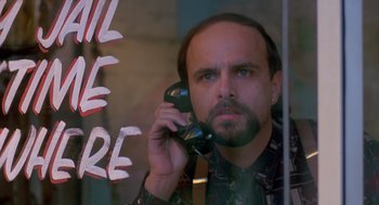 Movie still from “Midnight Run” (1988), directed by Martin Brest – A man is talking on a phone in front of a store window; Close Up shot, Low angle
