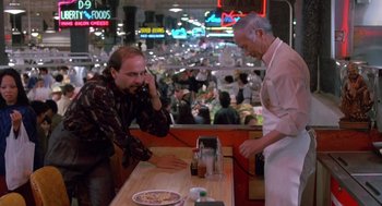 Movie still from “Midnight Run” (1988), directed by Martin Brest – A man talking on the phone at a pizza parlor; Medium shot, Low angle