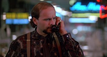 Movie still from “Midnight Run” (1988), directed by Martin Brest – A man talking on a cell phone while standing in front of a building; Close Up shot, High angle