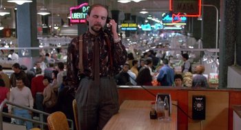 Movie still from “Midnight Run” (1988), directed by Martin Brest – A man standing at a table talking on a phone; Medium shot, Low angle