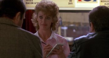 Movie still from “Midnight Run” (1988), directed by Martin Brest – A woman holding a cell phone in her hands; Close Up shot, Over the shoulder angle