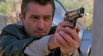 Movie still from “Midnight Run” (1988), directed by Martin Brest – A person holding a gun; Close Up shot, Low angle
