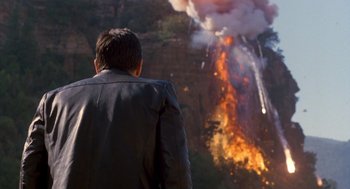 Movie still from “Midnight Run” (1988), directed by Martin Brest – A man in a leather jacket looking at a fire; Wide shot, Over the shoulder angle