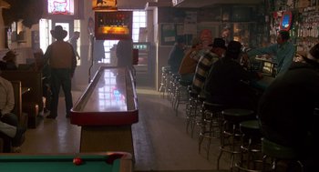 Movie still from “Midnight Run” (1988), directed by Martin Brest – A group of people sitting at a table in front of a bar; Wide shot, High angle