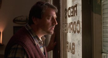 Movie still from “Midnight Run” (1988), directed by Martin Brest – A man leaning against a wall looking at the camera; Close Up shot, Low angle