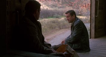 Movie still from “Midnight Run” (1988), directed by Martin Brest – Two men are sitting on a bench near a river; Wide shot, Over the shoulder angle