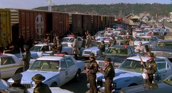 Movie still from “Midnight Run” (1988), directed by Martin Brest – A large group of police officers standing next to a bunch of parked cars; Extreme Wide shot, High angle