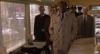 Movie still from “Midnight Run” (1988), directed by Martin Brest – A group of men standing around a table; Medium shot, Over the shoulder angle