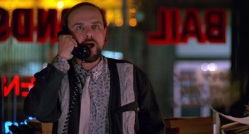 Movie still from “Midnight Run” (1988), directed by Martin Brest – A man talking on a phone while standing in front of neon signs; Medium shot, Low angle