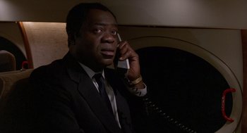 Movie still from “Midnight Run” (1988), directed by Martin Brest – A man in a suit and tie talking on a phone; Close Up shot, High angle