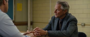 Movie still from “Midnight Special” (2016), directed by Jeff Nichols – An older man sitting at a table with his hands clasped together; Close Up shot, Over the shoulder angle