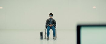Movie still from “Midnight Special” (2016), directed by Jeff Nichols – A young man sitting in a chair next to a speaker; Wide shot, Over the shoulder angle