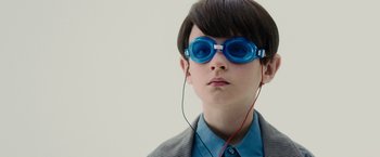Movie still from “Midnight Special” (2016), directed by Jeff Nichols – A young boy wearing goggles and listening to music; Close Up shot, Over the shoulder angle