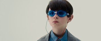Movie still from “Midnight Special” (2016), directed by Jeff Nichols – A young boy wearing goggles and listening to music; Close Up shot, Over the shoulder angle