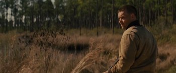 Movie still from “Midnight Special” (2016), directed by Jeff Nichols – A man standing in a field holding a rifle; Medium shot, Over the shoulder angle