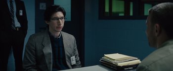 Movie still from “Midnight Special” (2016), directed by Jeff Nichols – A man sitting at a table in front of a stack of papers; Medium shot, Over the shoulder angle