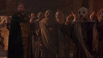 Movie still from “Mighty Aphrodite” (1995), directed by Woody Allen – A group of people wearing masks in a room; Medium shot, Low angle