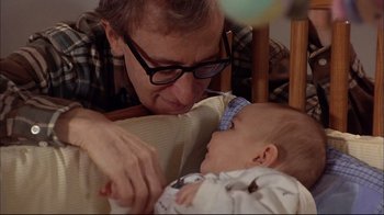 Movie still from “Mighty Aphrodite” (1995), directed by Woody Allen – An older man holding a baby in his arms; Close Up shot, Over the shoulder angle