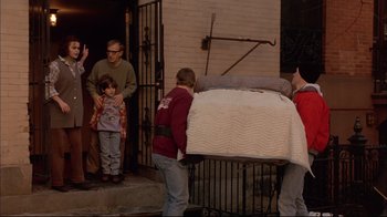 Movie still from “Mighty Aphrodite” (1995), directed by Woody Allen – A group of people standing next to a bed; Wide shot, Over the shoulder angle