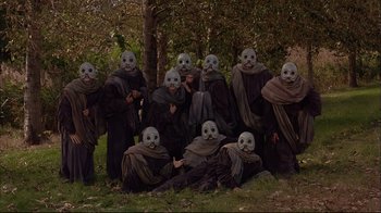 Movie still from “Mighty Aphrodite” (1995), directed by Woody Allen – A group of people with masks on posing for a picture; Wide shot, High angle
