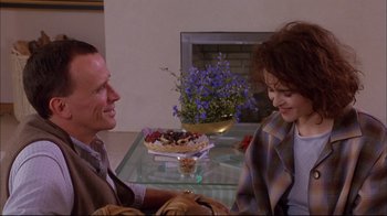 Movie still from “Mighty Aphrodite” (1995), directed by Woody Allen – A man and a woman sitting in front of a cake; Medium shot, Over the shoulder angle