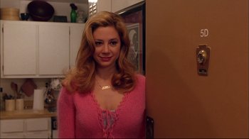 Movie still from “Mighty Aphrodite” (1995), directed by Woody Allen – A woman in a pink sweater posing for a picture; Close Up shot, High angle