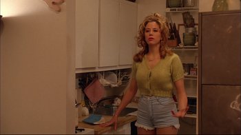 Movie still from “Mighty Aphrodite” (1995), directed by Woody Allen – A woman standing in a kitchen wearing shorts and a yellow shirt; Medium shot, Low angle